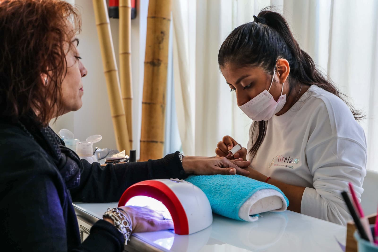 A hand positioned under a UV nail curing lamp