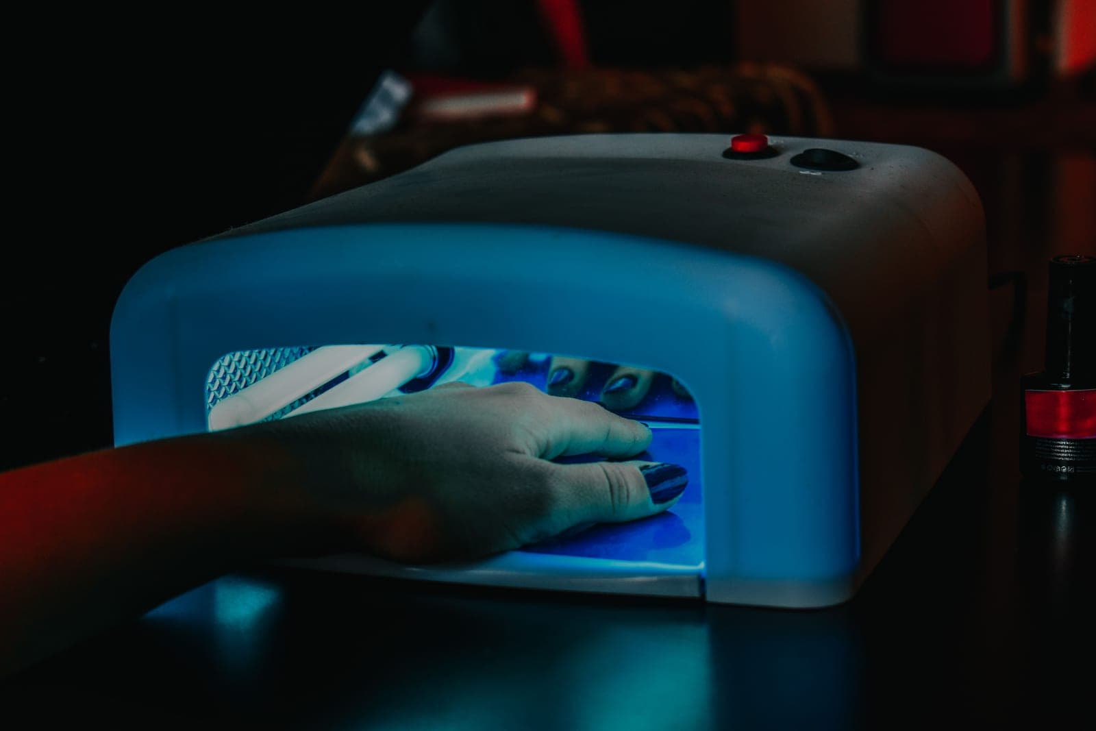 A hand curing gel polish under a small LED nail lamp